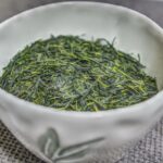 Foglie essiccate di tè verde Gyokuro (Camellia sinensis) in una ciotola giapponese, ottenute da coltivazione ombreggiata e caratterizzate da un elevato contenuto di L-teanina.